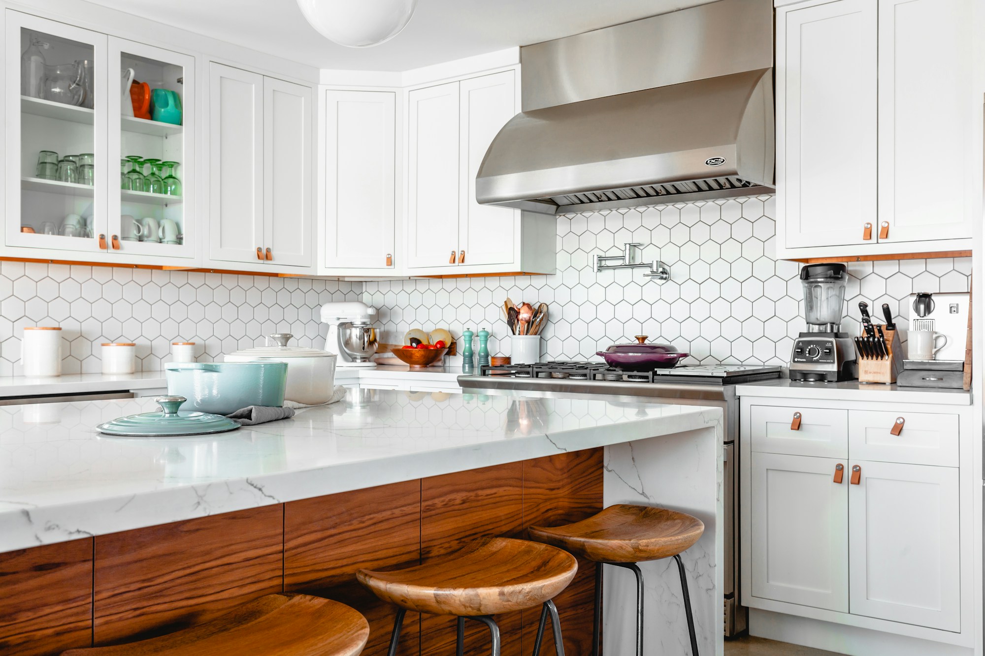 Light-filled kitchen with a marble island, white cabinetry and warm walnut details